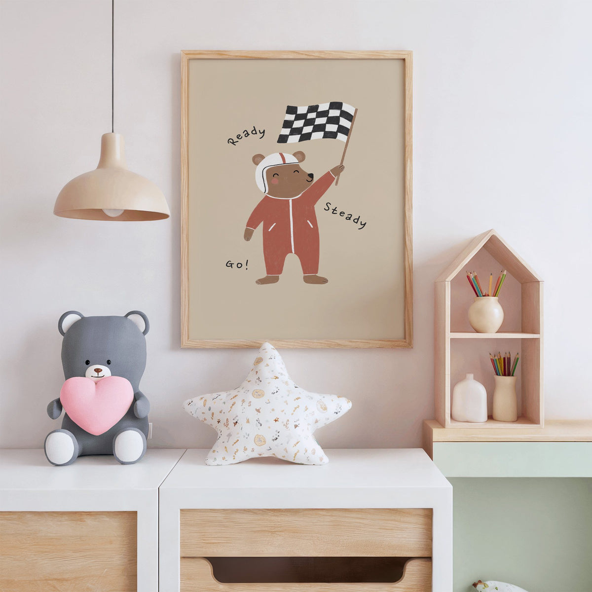 Ready steady go racing bear nursery print in an oak frame above a white dresser with a star pillow and house shelf