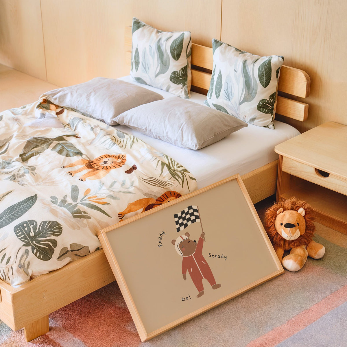 Landscape ready steady go racing bear nursery print in an oak frame leaning on a kids bed by a lion plush