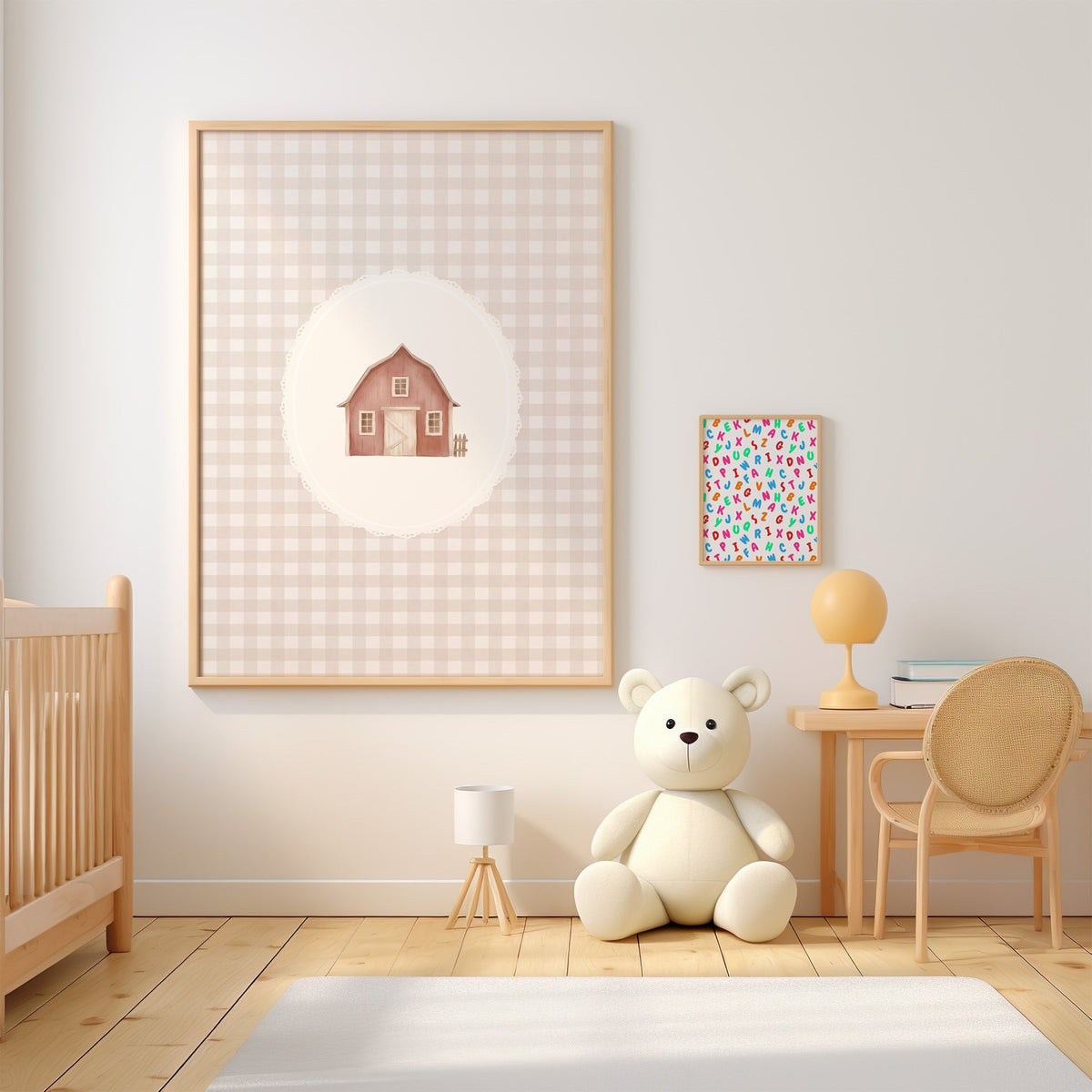Little red barn in a lace oval on gingham nursery print in an oak frame above a wooden crib beside a cream teddy bear