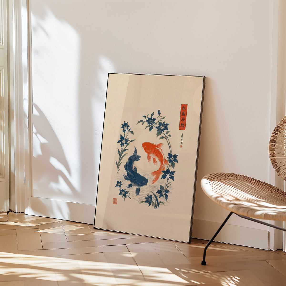 red and blue koi with blue flowers print in a black frame leaning on a herringbone floor beside a woven rattan chair
