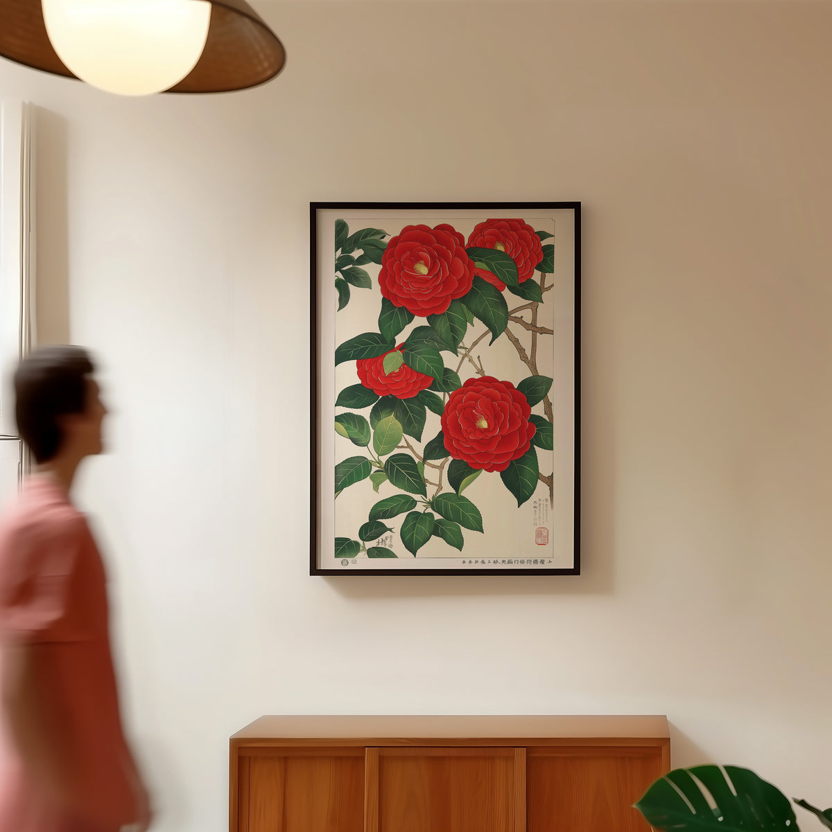 Red camellia woodblock-style print in a black frame in a hallway under a rattan pendant