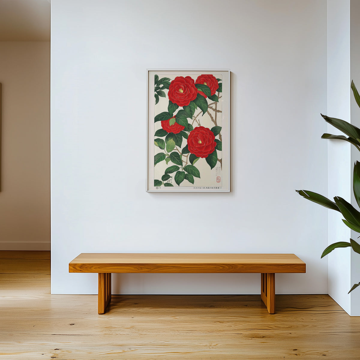 Red camellia woodblock-style print shown in a white frame above a wooden entryway bench