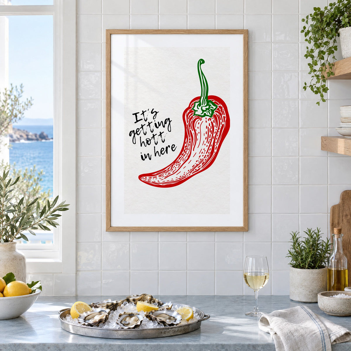 It's getting hott red chili engraving print in an oak frame on white tiles above a marble counter with oysters and lemons by a sea view