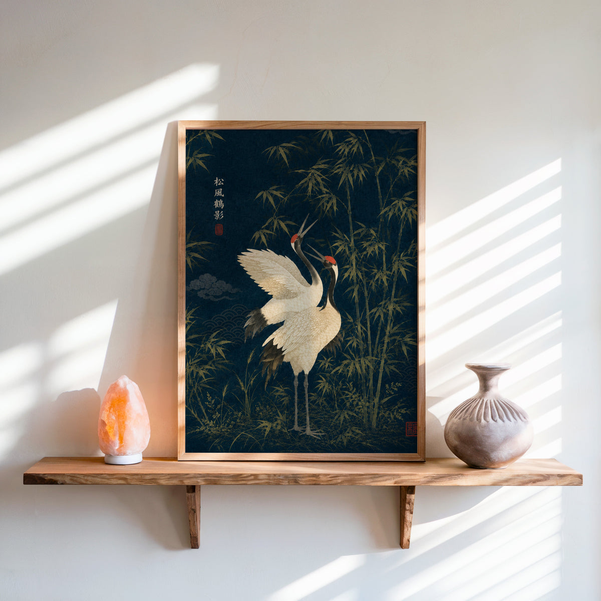 red-crowned cranes and bamboo on navy print in an oak frame on a live-edge wall shelf with a salt lamp and clay vase