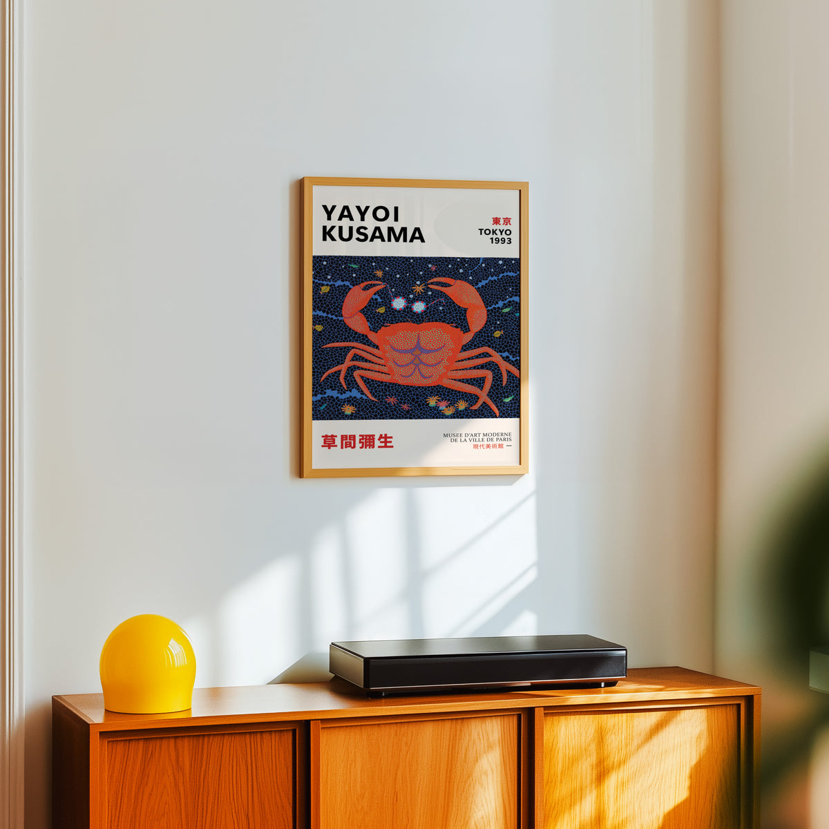 Yayoi Kusama inspired red dotted crab print above a sideboard with a yellow lamp