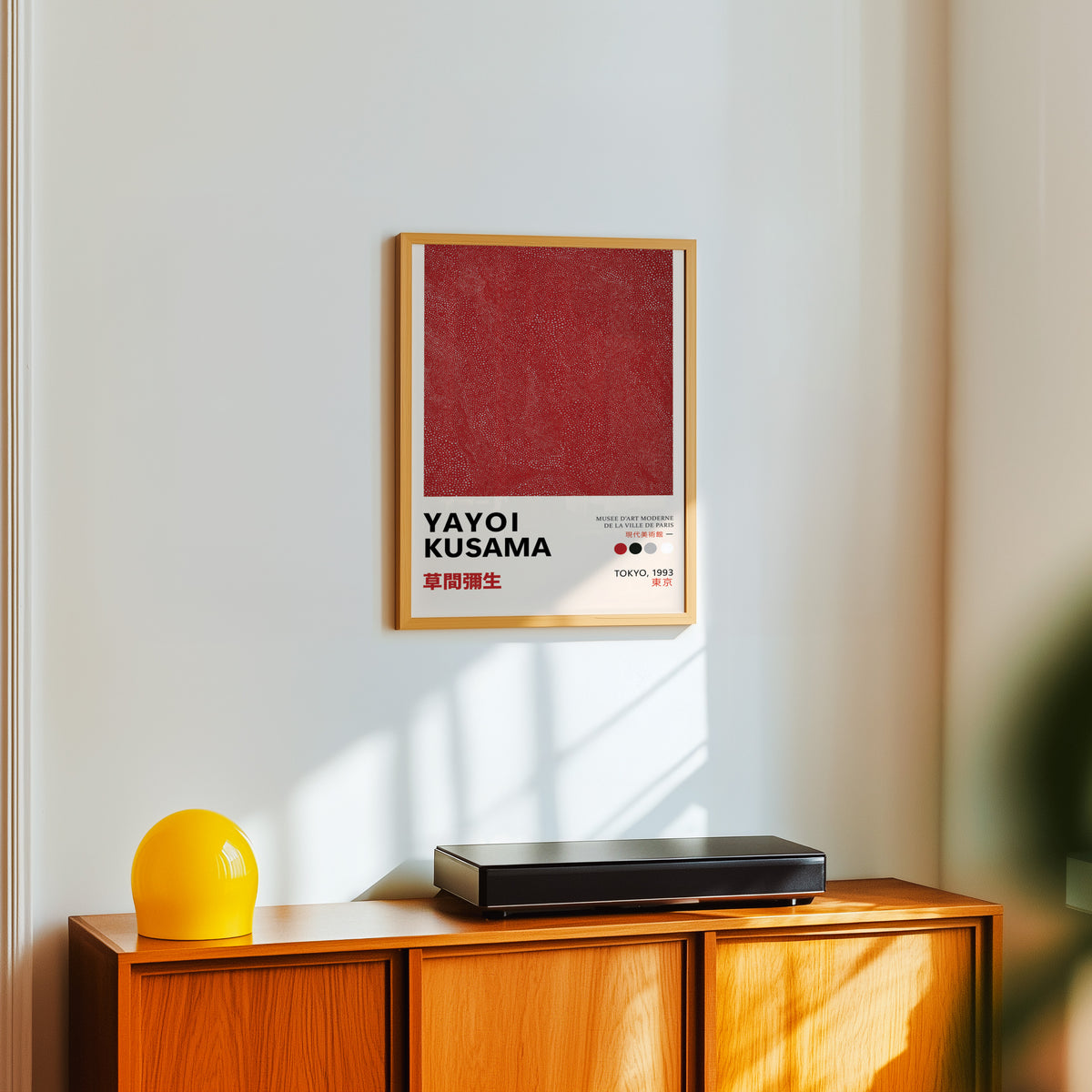 Yayoi Kusama inspired red dotted texture print above a sideboard with a yellow lamp