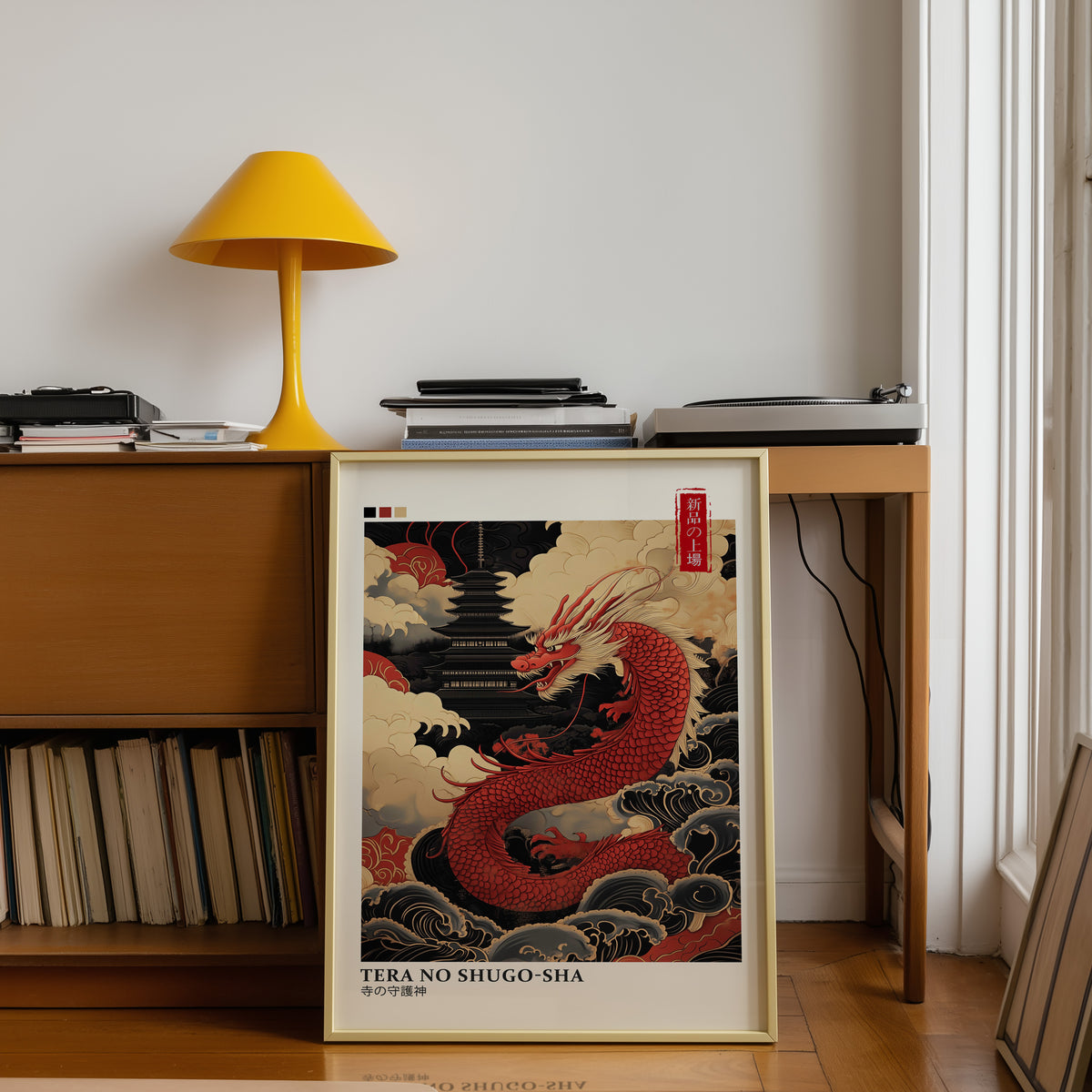Red dragon guarding black pagoda print shown in a gold frame below a teak desk with a yellow lamp