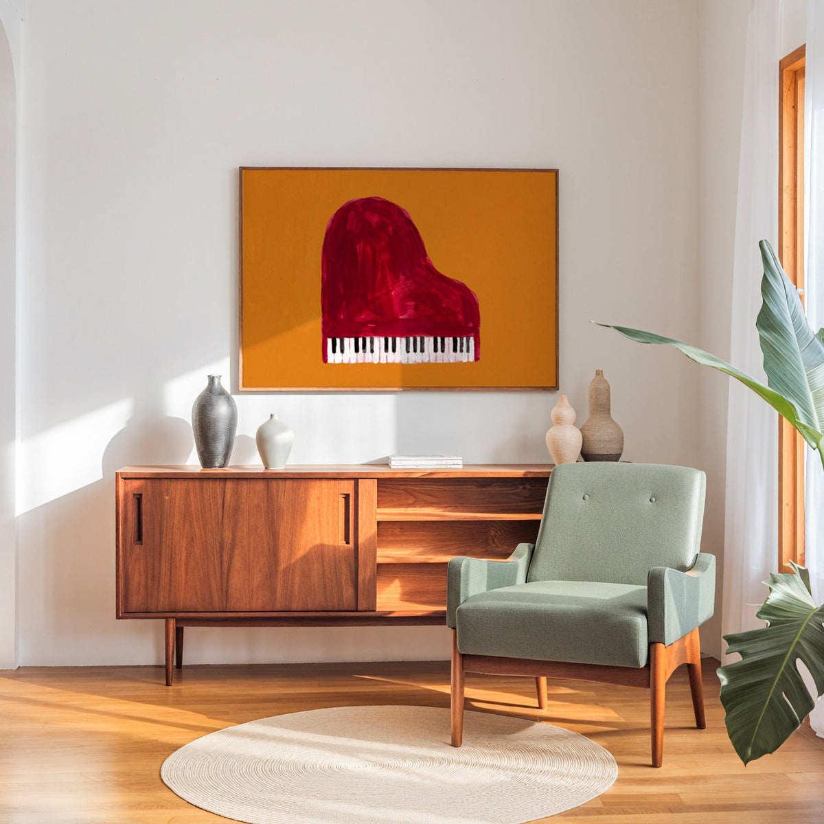 Hand-painted piano print in a walnut frame above a sideboard beside a sage armchair