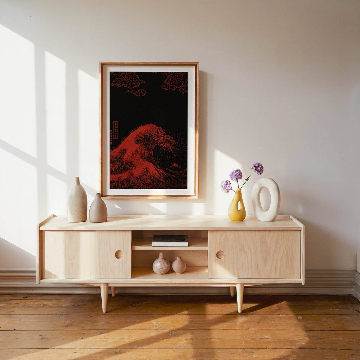 red Great Wave on black print shown in a wood frame with a white mat above a pale wood media console