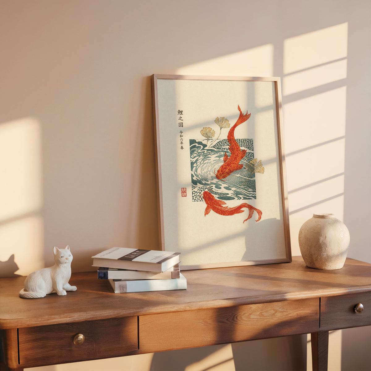 red koi with ginkgo and wave block print shown in a rose gold frame leaning on a wooden writing desk with books