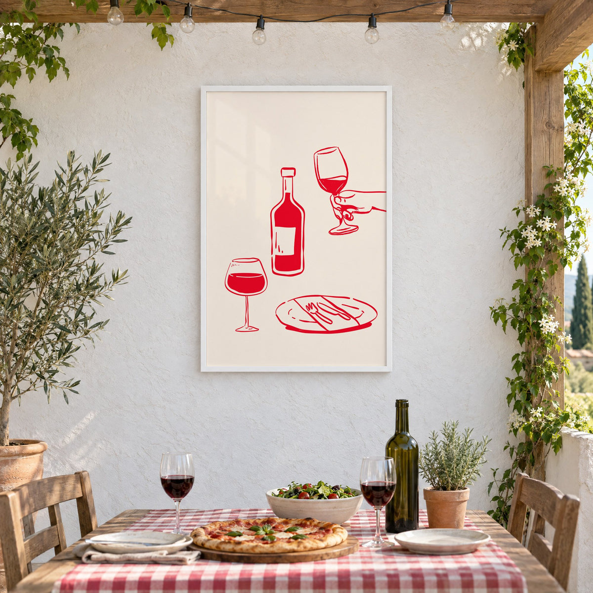 Red line wine bottle and dinner table print in a white frame on a stucco wall above a checked-cloth table with pizza and red wine