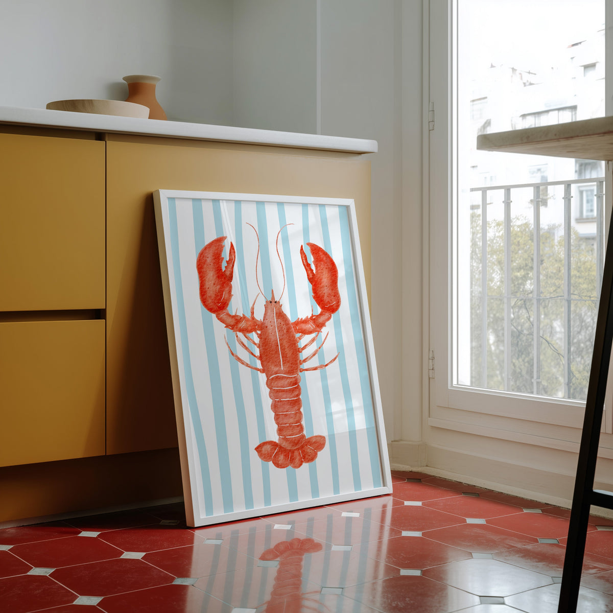 Red lobster print in a white frame against yellow cabinets on a red tiled floor