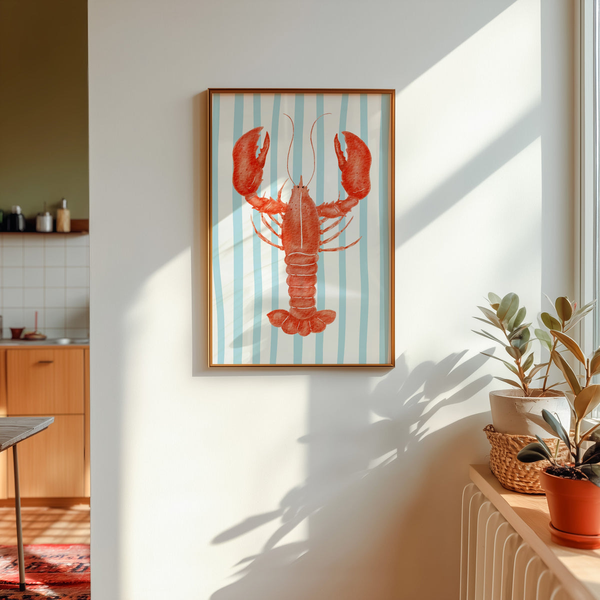 Red lobster print shown in a gold frame in sunlight with plants and a kitchen beyond