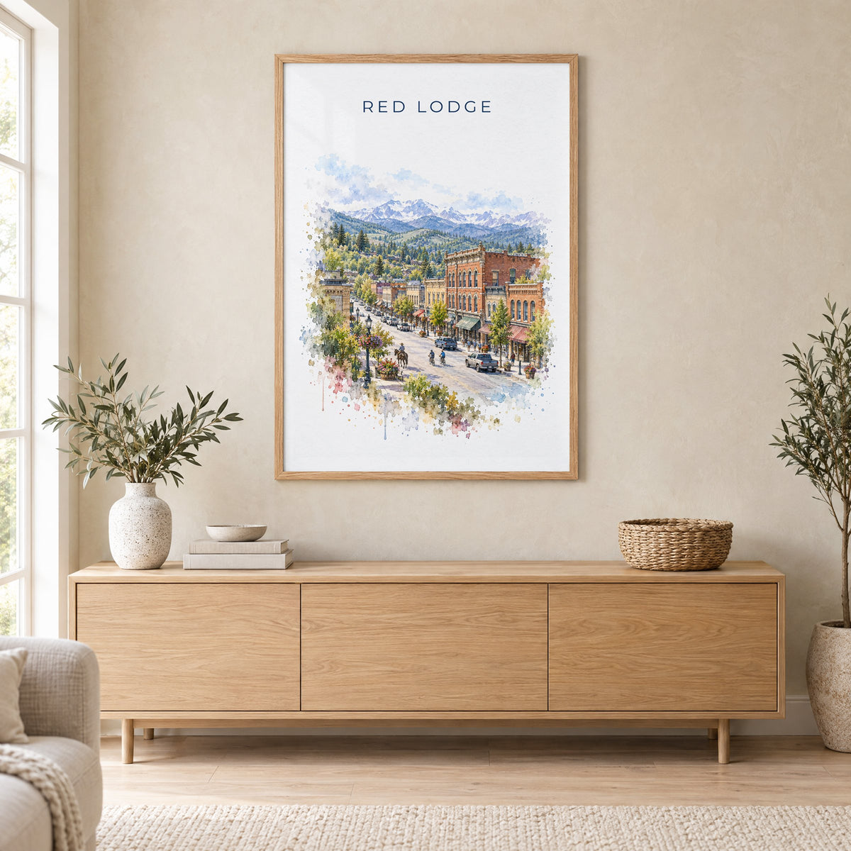 Red Lodge, Montana watercolor print in an oak frame above a light wood sideboard in a Scandinavian living room