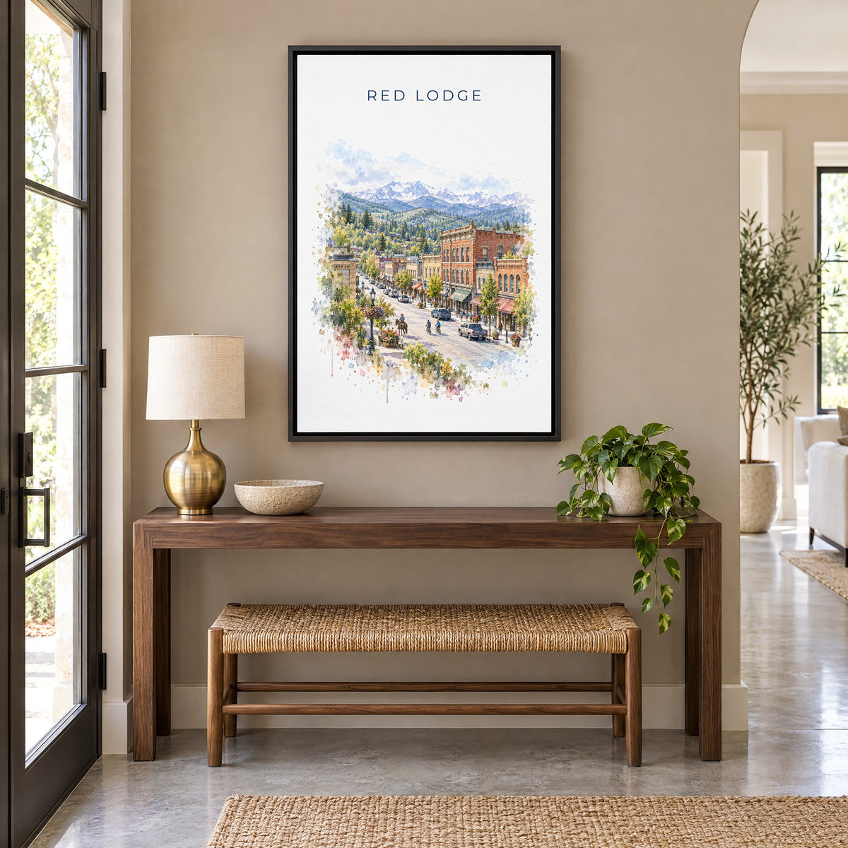 Red Lodge, Montana watercolor print as a black floater canvas above a walnut console and woven bench in an entryway