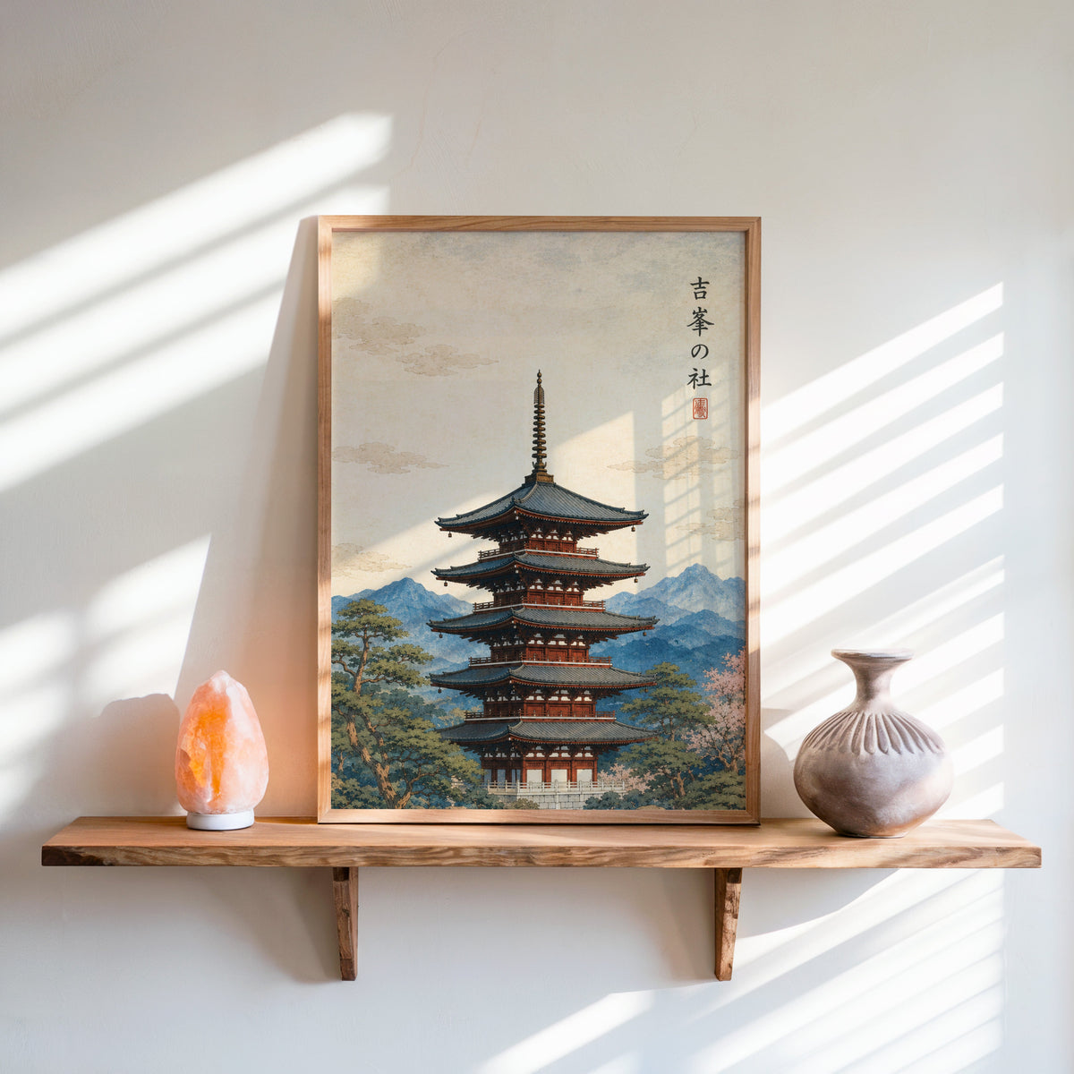 red pagoda with blue mountains print in an oak frame on a live-edge wall shelf with a salt lamp and clay vase