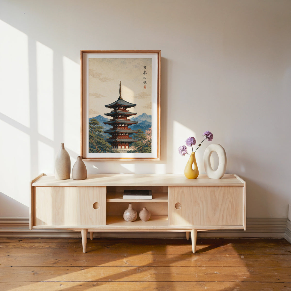 red pagoda with blue mountains print shown in a wood frame with a white mat above a pale wood media console