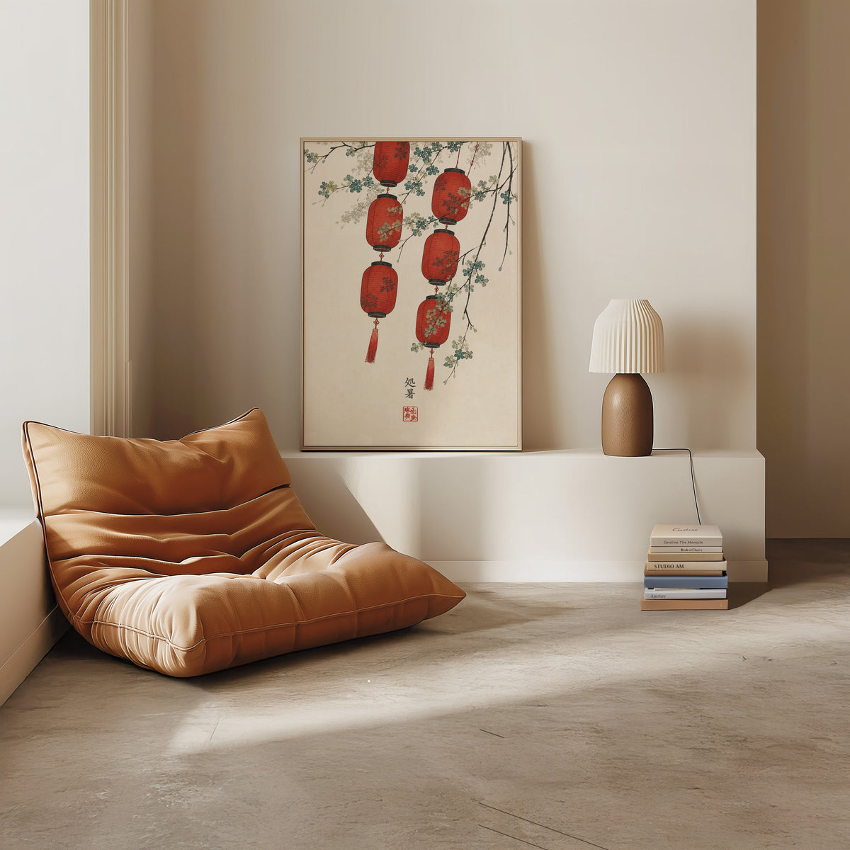 red paper lanterns with blossom branch print in a light oak frame on a white ledge by a tan leather floor chair