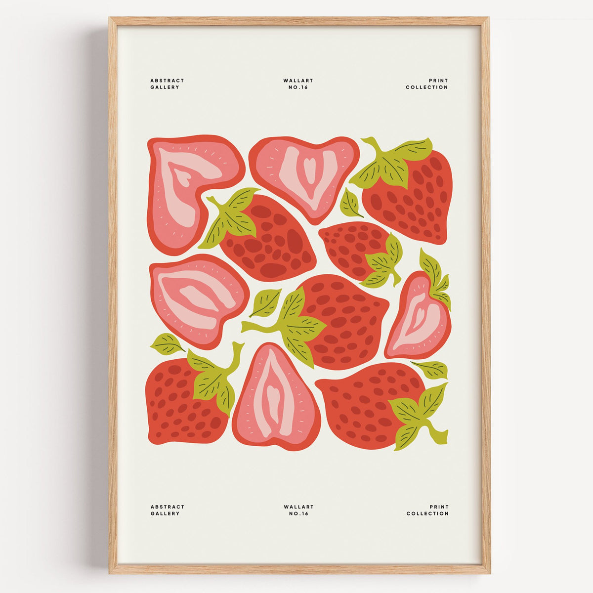 Red and pink strawberry halves pattern print in a light oak frame on a plain white wall
