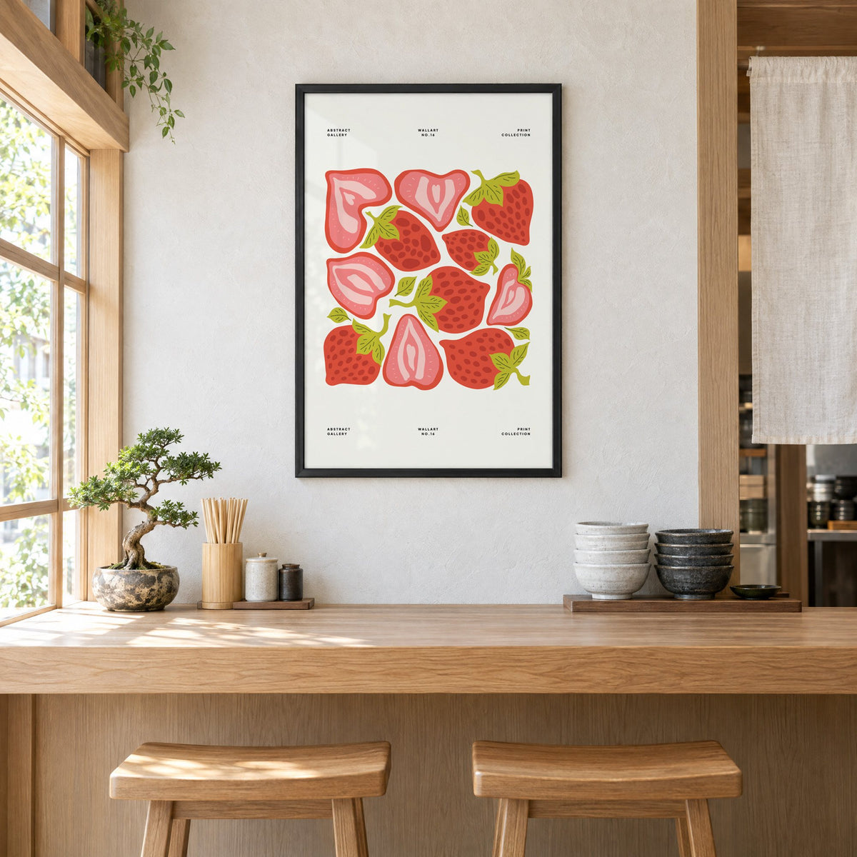 Red and pink strawberry halves pattern print in a black frame above a light wood ramen counter with stools and stacked bowls