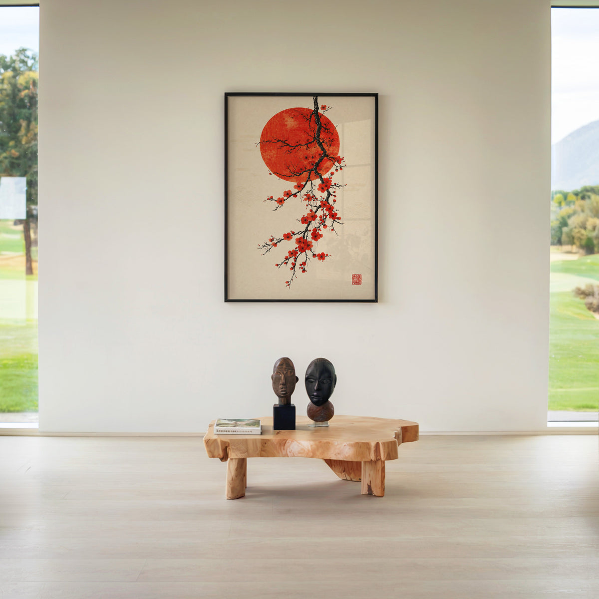 red blossom ink branch with red sun print in a black frame above a live-edge wood coffee table between garden windows