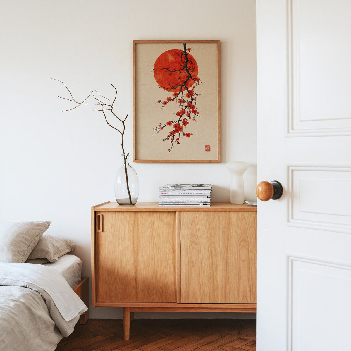 red blossom ink branch with red sun print in an oak frame above an oak sideboard in a bedroom with linen bedding