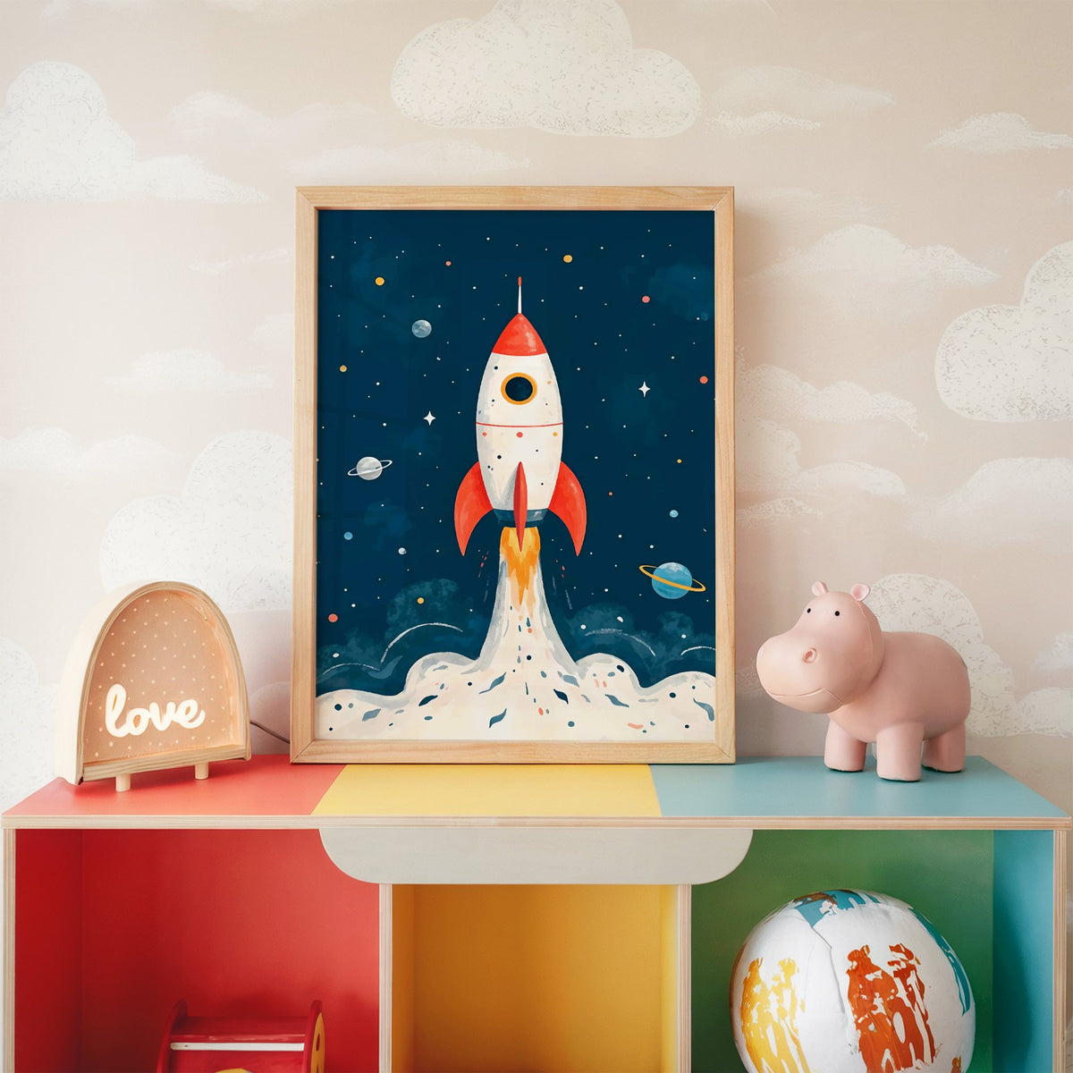 Red rocket launching past planets nursery print in an oak frame on a rainbow toy shelf against cloud wallpaper
