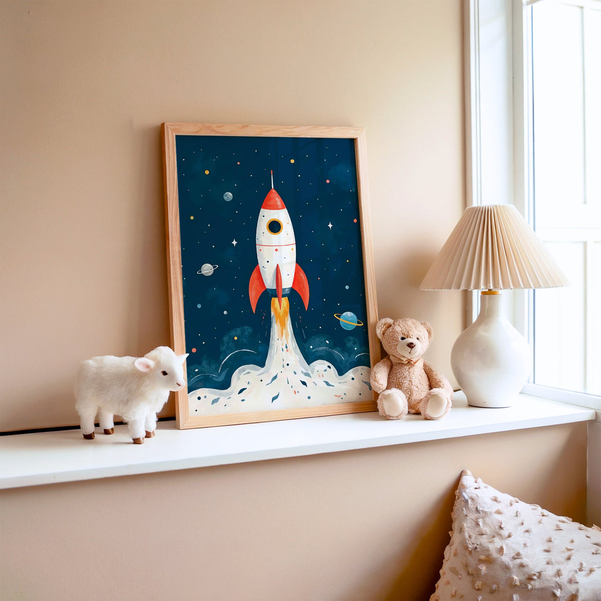 Red rocket launching past planets nursery print in an oak frame on a window ledge with a toy lamb and teddy