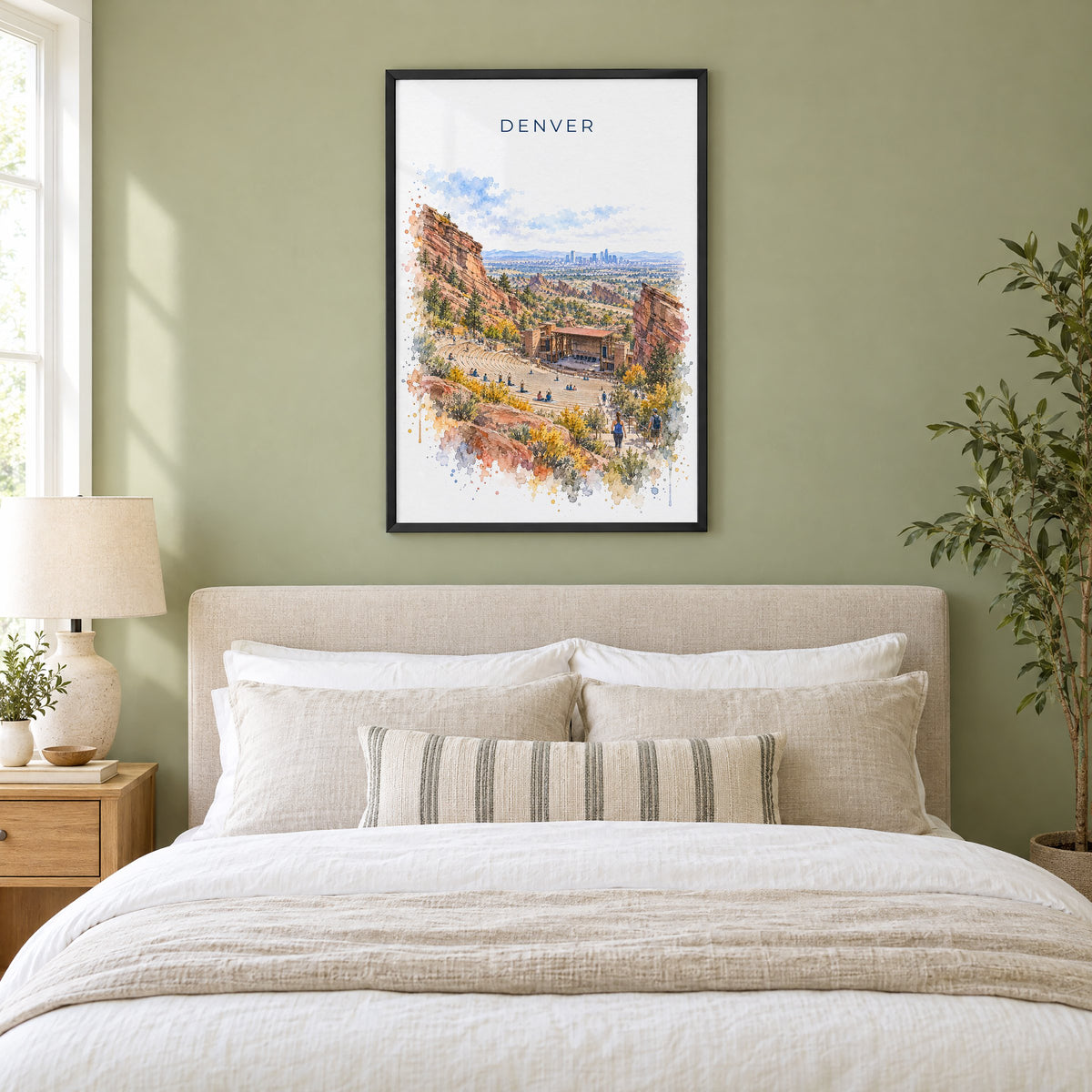 Red Rocks Amphitheatre watercolor print in a black frame above an upholstered headboard in a sage green bedroom