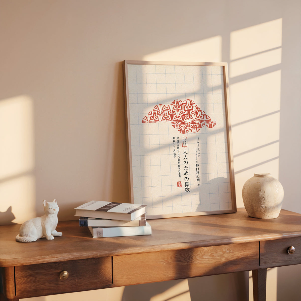 red seigaiha cloud on grid paper print shown in a rose gold frame leaning on a wooden writing desk with books