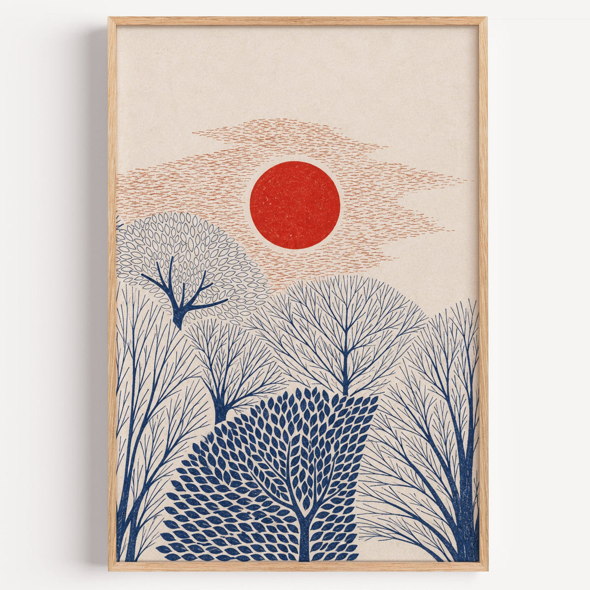 red sun over navy trees print in a light oak frame on a plain white wall