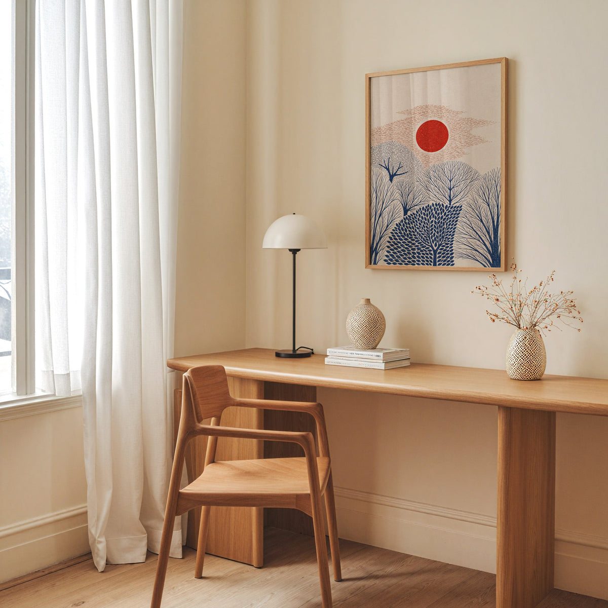 red sun over navy trees print in an oak frame above a long oak desk with a white dome lamp and woven vases