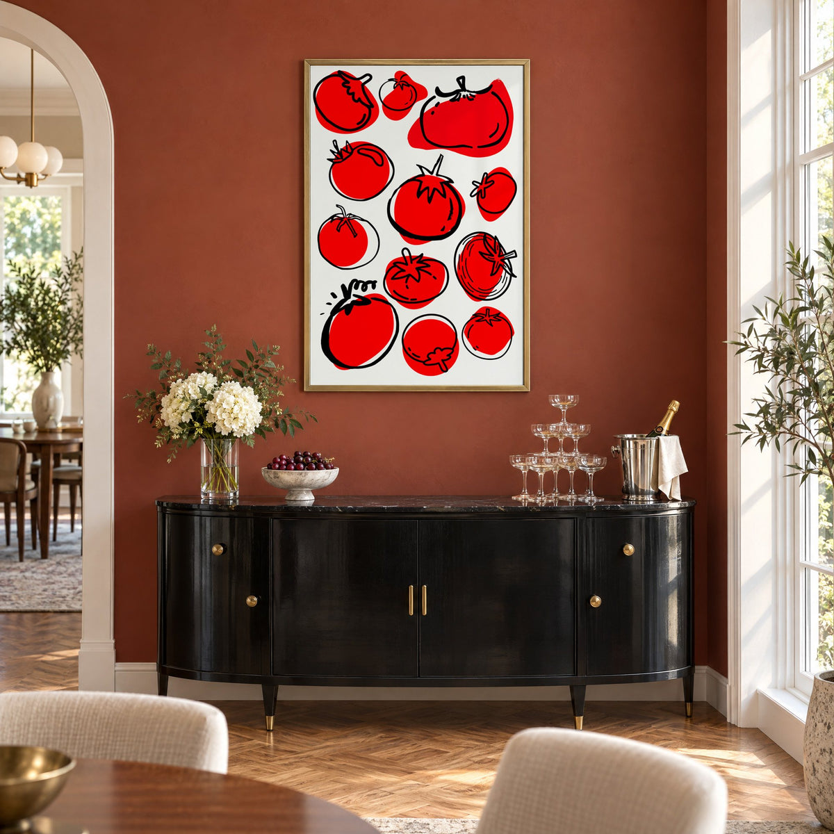 Red tomatoes offset line pattern print in a brass frame on a terracotta wall above a black buffet with a champagne tower