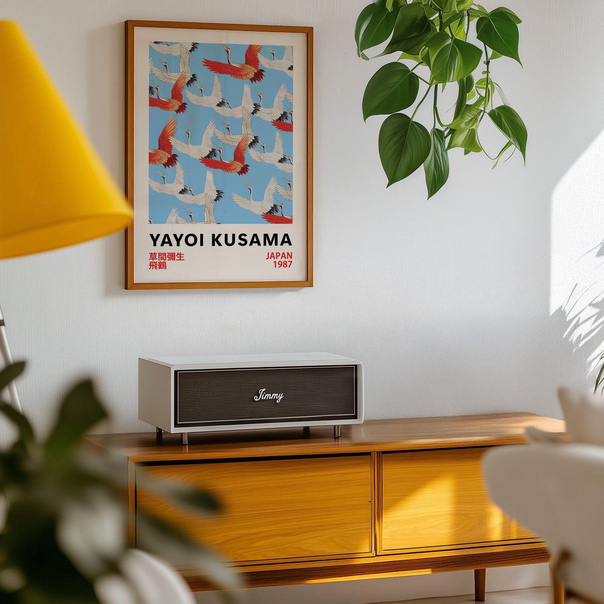 Yayoi Kusama inspired red and white flying cranes print in an oak frame above a teak sideboard with pothos