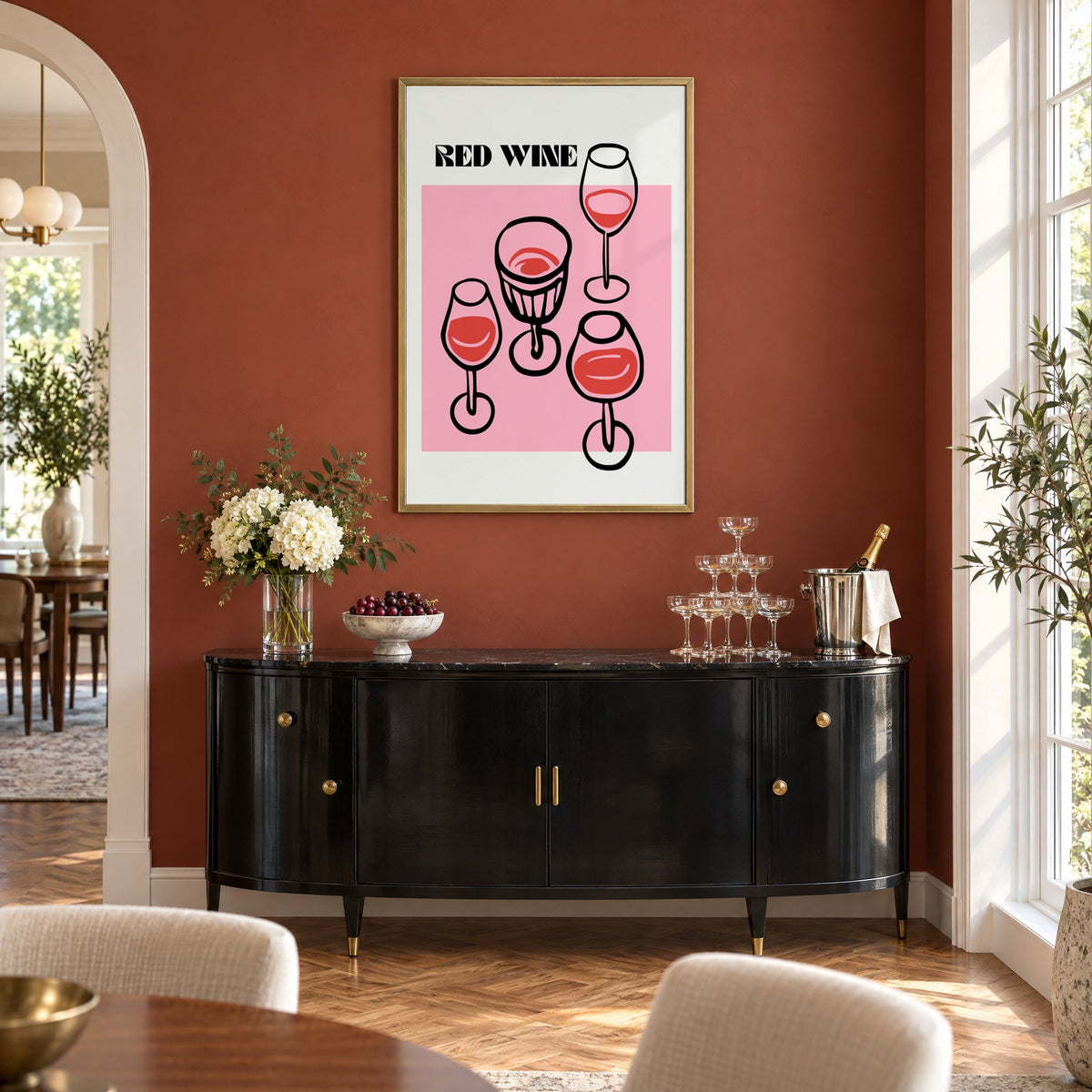 RED WINE four glasses pink print in a brass frame on a terracotta wall above a black buffet with a champagne tower