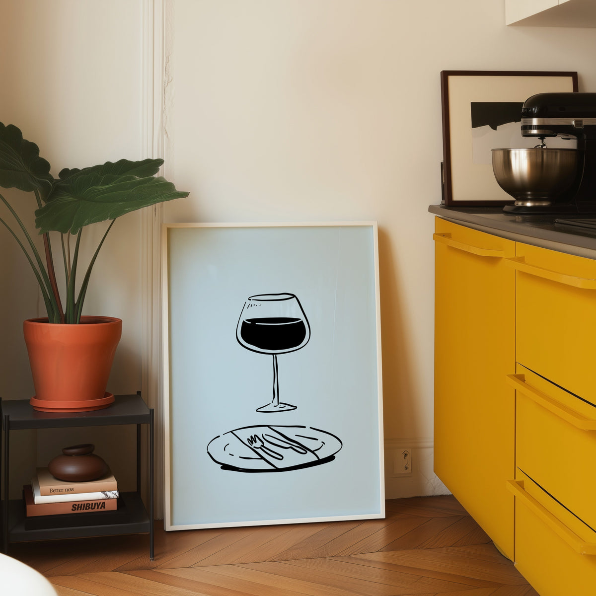 Red wine glass print in a white frame on parquet beside a bright yellow kitchen