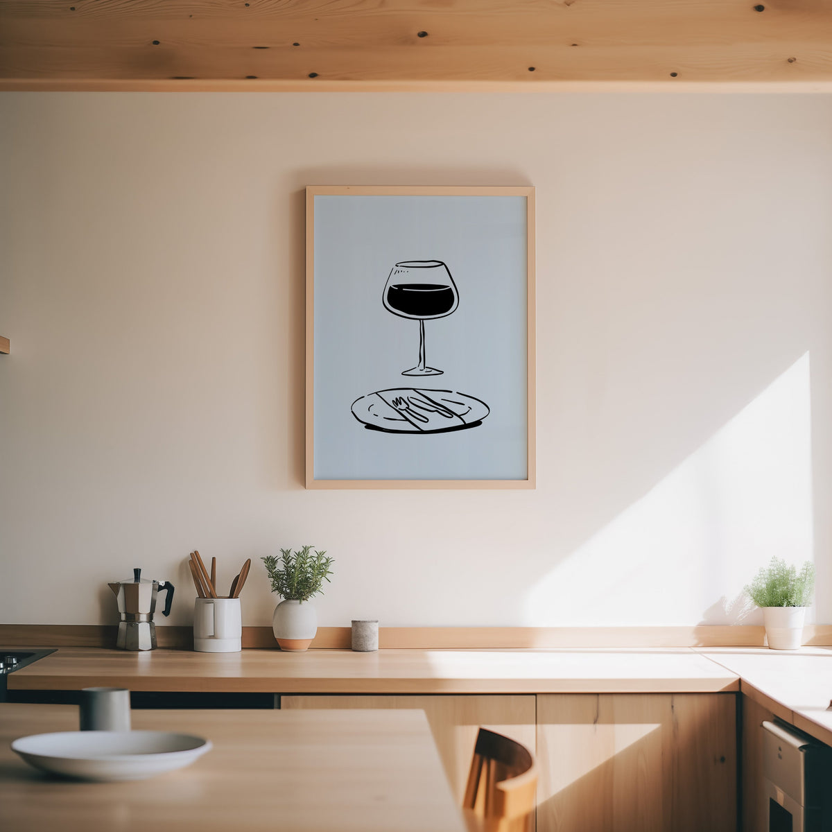 Red wine glass print in an oak frame above a wood counter with a moka pot and herbs