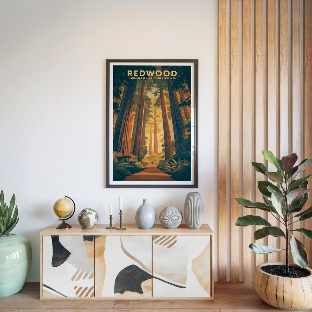 Redwood National Park print in a black frame above a light wood sideboard with a globe and ceramic vases