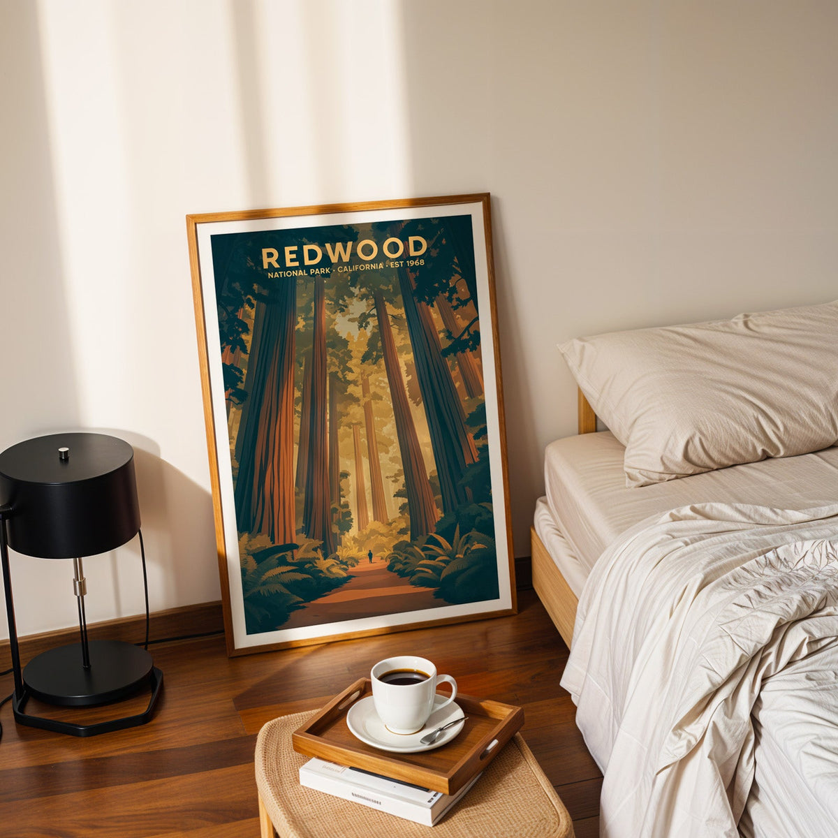Redwood National Park print in an oak frame leaning on a bedroom floor beside the bed and a coffee tray