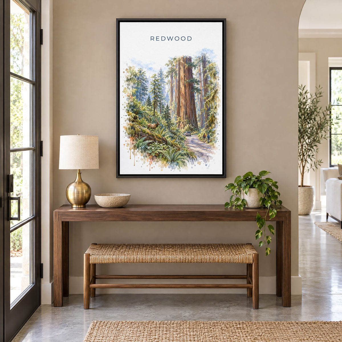 Redwood National Park watercolor print as a black floater canvas above a walnut console and woven bench in an entryway