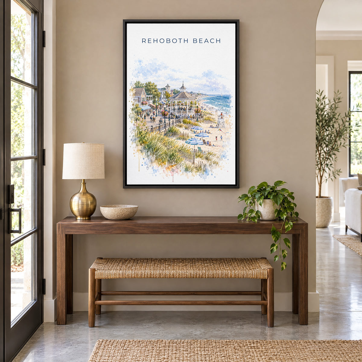 Rehoboth Beach watercolor print as a black floater canvas above a walnut console and woven bench in an entryway