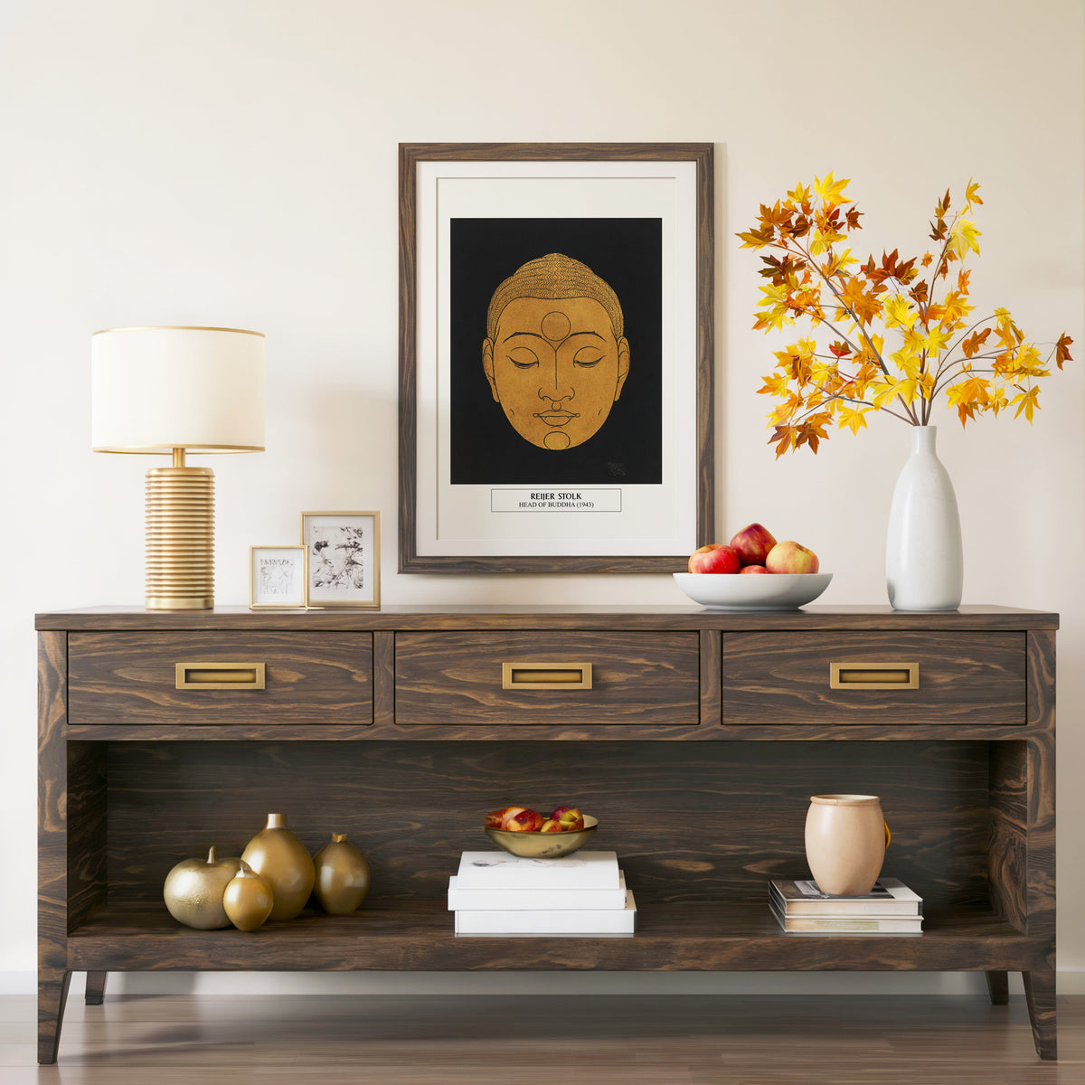 Head of Buddha print in a walnut frame above a console with autumn branches
