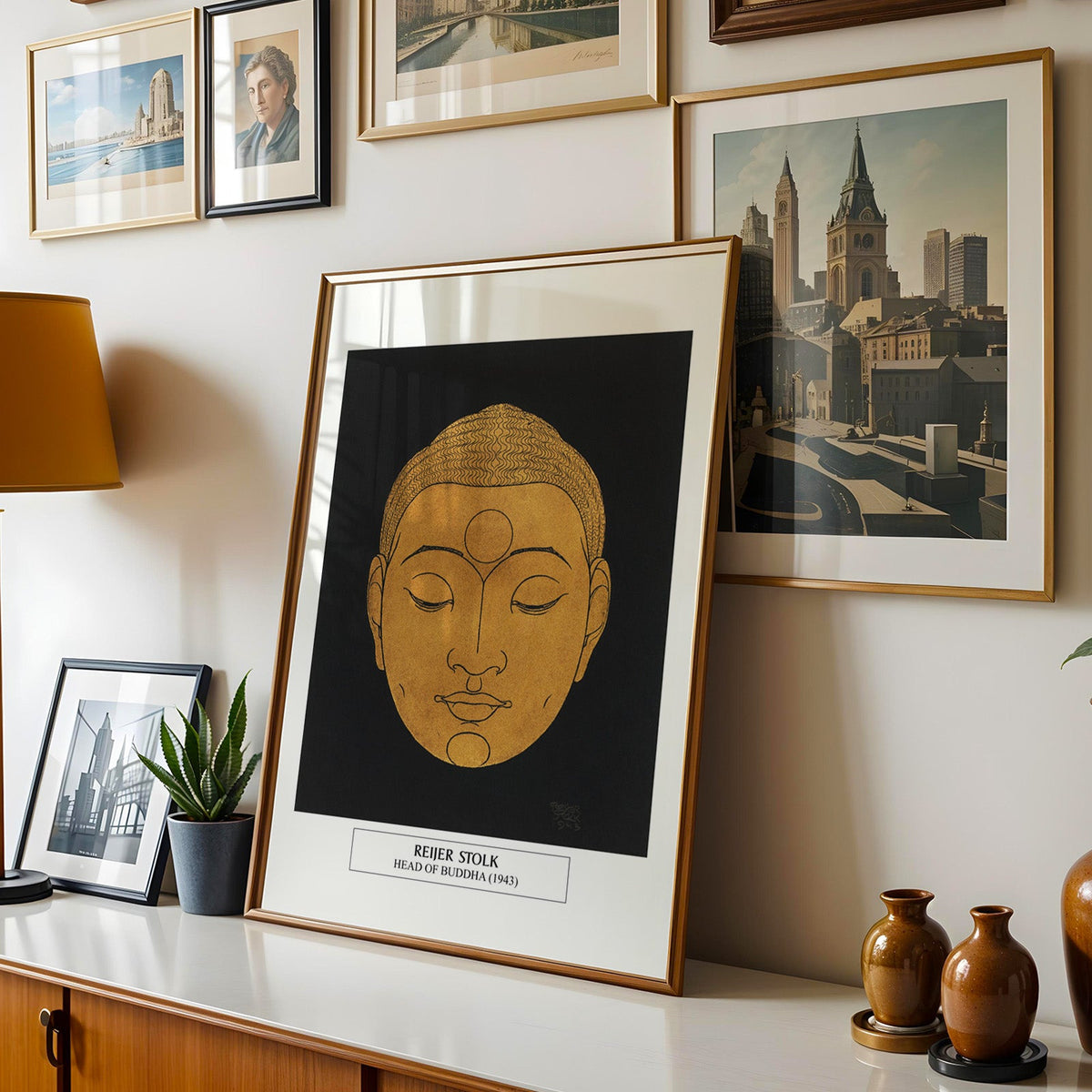 Stolk print shown in a gold frame leaning on a sideboard in a gallery wall