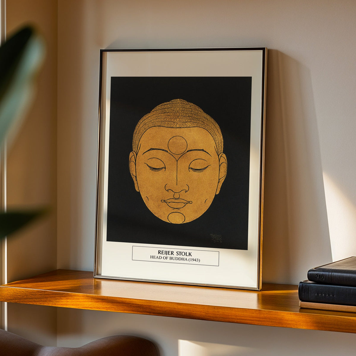 Head of Buddha print in a black frame on a walnut shelf in warm evening light