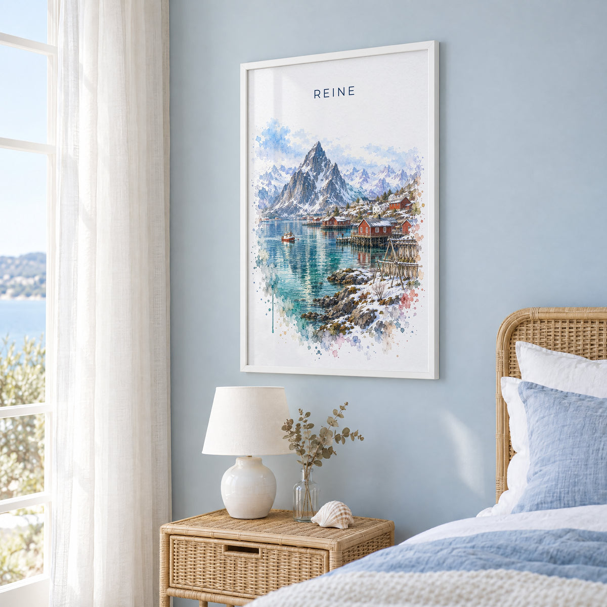 Reine, Norway watercolor print in a white frame on a pale blue wall beside a rattan bed in a coastal bedroom