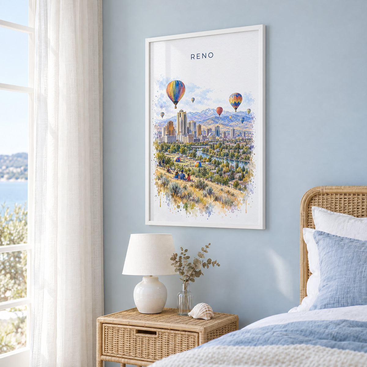 Reno, Nevada watercolor print in a white frame on a pale blue wall beside a rattan bed in a coastal bedroom