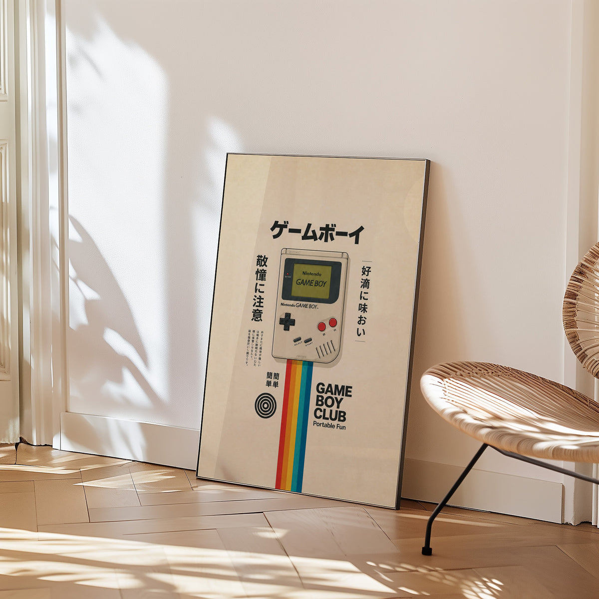 retro handheld game console with rainbow print in a black frame leaning on a herringbone floor beside a woven rattan chair