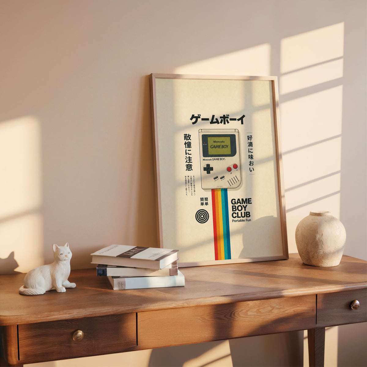 retro handheld game console with rainbow print shown in a rose gold frame leaning on a wooden writing desk with books