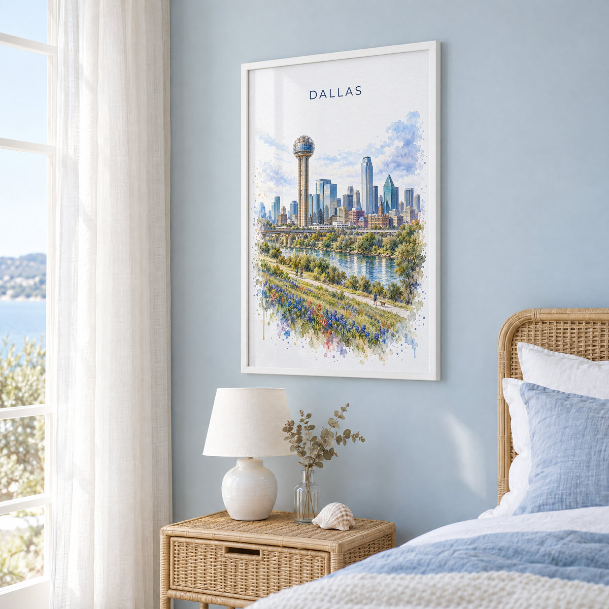 Reunion Tower Dallas watercolor print in a white frame on a pale blue wall beside a rattan bed in a coastal bedroom