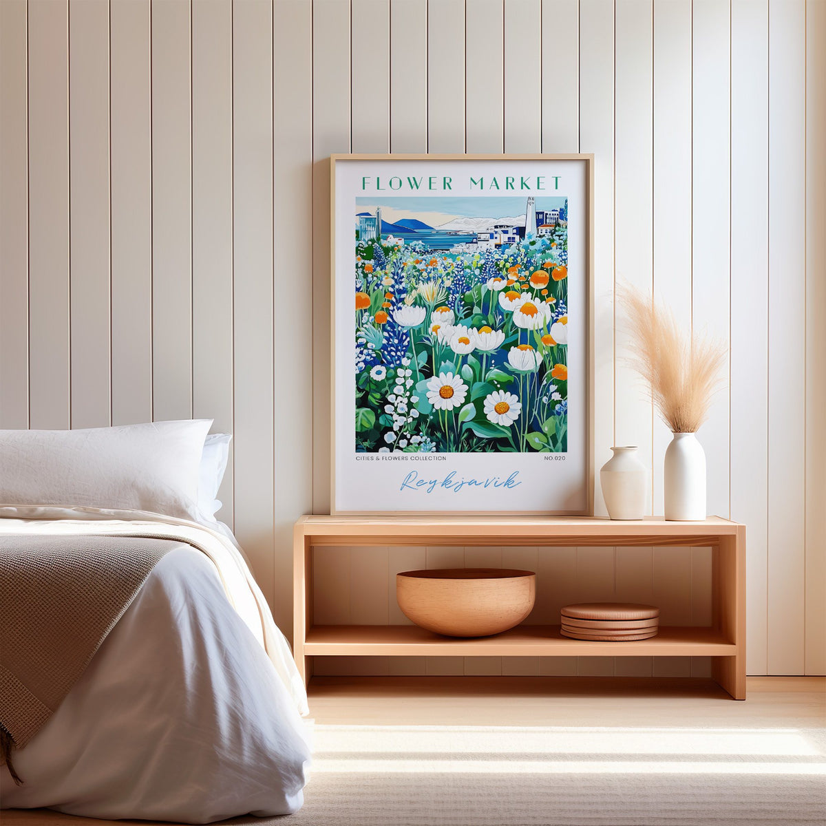 Reykjavik flower market print in an oak frame on a wood bench against a white shiplap bedroom wall with pampas grass
